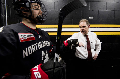 Head coach Jim Madigan bumps fists with a player before the Beanpot final. Photo by Matthew Modoono/Northeastern University