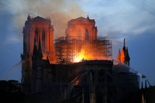 Firefighters tackled the blaze as flames and smoke rose from Notre Dame cathedral as it burned in Paris, Monday, April 15, 2019. Massive plumes of yellow brown smoke filled the air above Notre Dame Cathedral and ash fell on tourists and others around the island that marks the center of Paris. (AP Photo/Michel Euler)