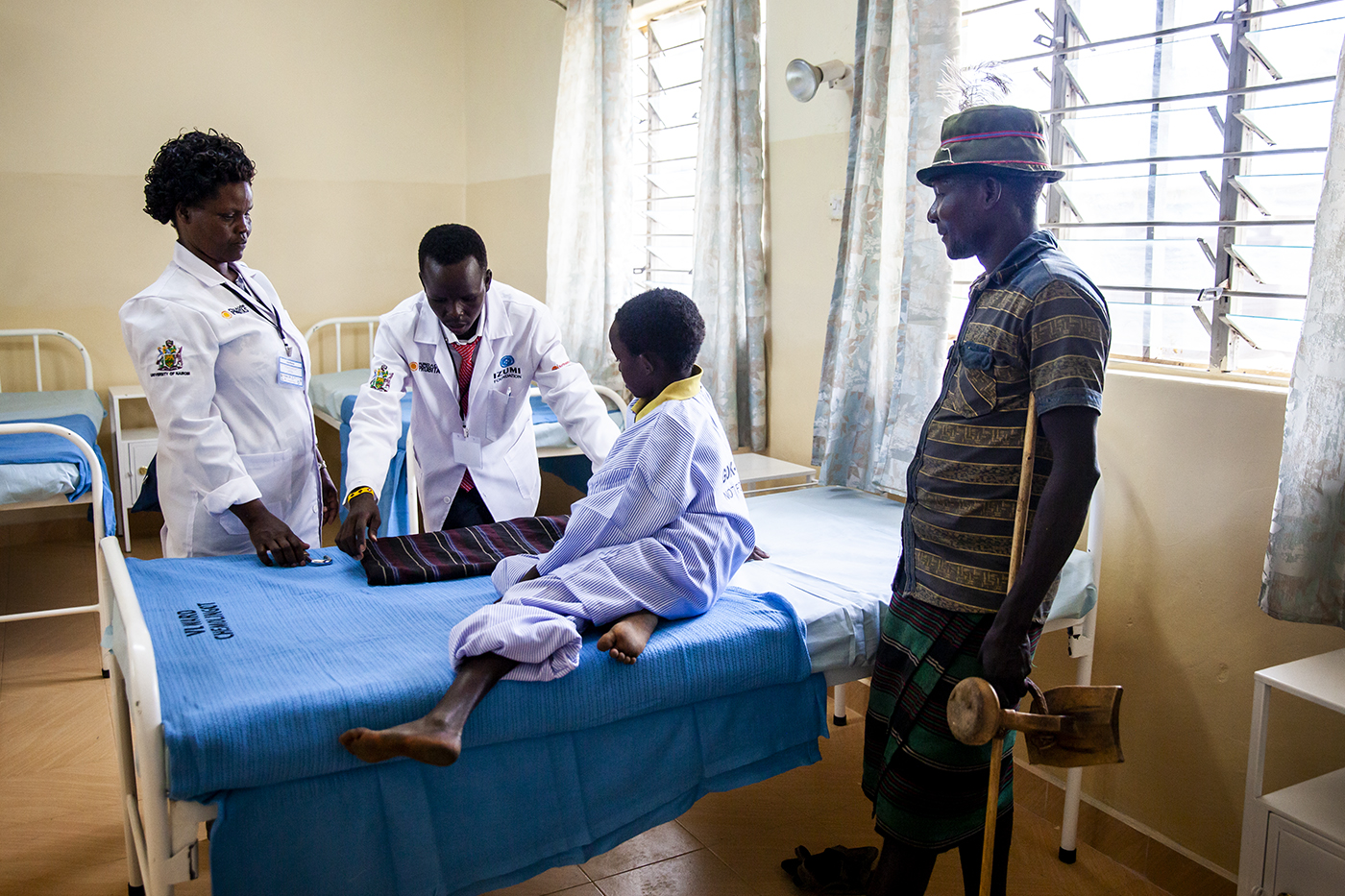 A nurse and pharmacist admit 10-year old Lopeto Losile to the new ward of the Chemolingot Sub-County Hospital. Losile’s father observes the process. Photo by Natalia Jidovanu for Northeastern University