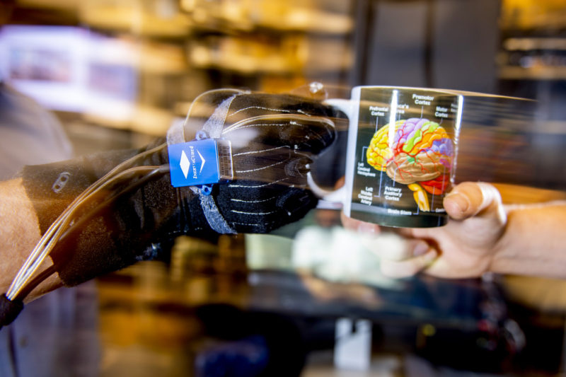 Researchers at Northeastern are studying how humans coordinate hand-offs with one another, and teaching robots to do the same. This glove covered in sensors provides information about how a person’s hand moves to grasp a mug.  Photo by Matthew Modoono/Northeastern University