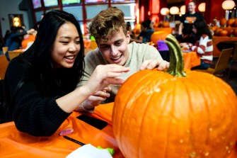 Two students carve a pumpkin