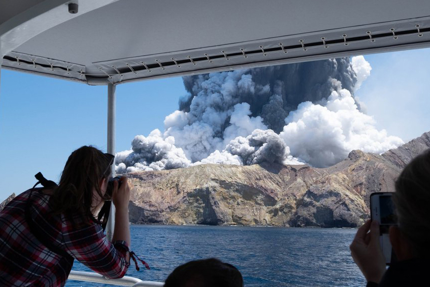 Tourists taking pictures of clouds coming from a volcano