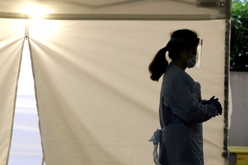 A nurse at a drive-up coronavirus testing station set up by the University of Washington Medical Center wears a face shield and other protective gear as she waits by a tent on March 13, 2020, in Seattle. AP Photo/Ted S. Warren