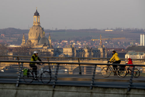 Cyclists in Dresden, Germany, cross the Waldschlösschen Bridge in the morning, with the historic old town skyline in the background. Photo by: Robert Michael/picture-alliance/dpa/AP Images