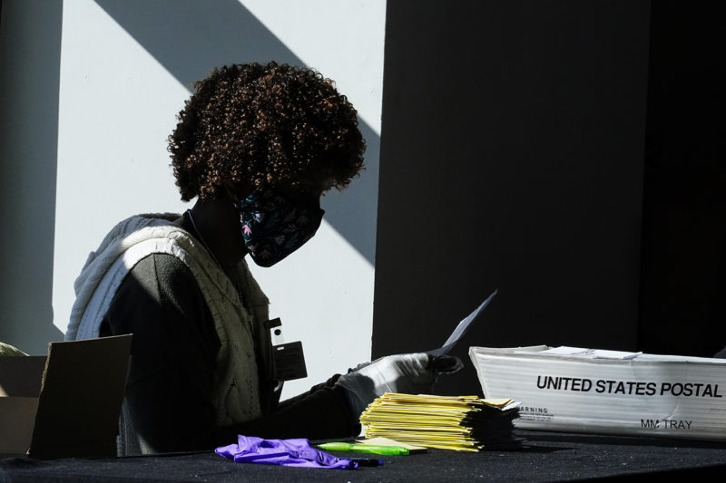 An election worker handles ballots as vote counting in the general election continues at State Farm Arena on Nov. 4, 2020, in Atlanta. AP Photo by Brynn Anderson