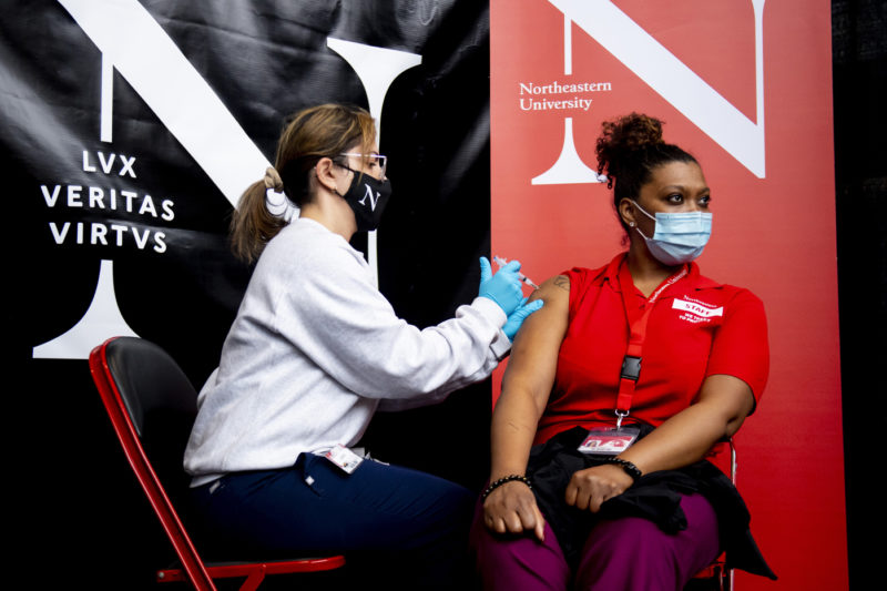 Nurse practitioner Jackie Fox administers the first Moderna COVID-19 vaccine to Iloisa Teixeira, a staff member at Northeastern’s Cabot Testing Center. Photo by Ruby Wallau/Northeastern University