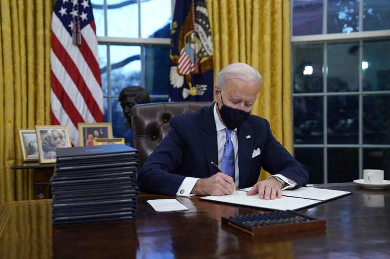 President Joe Biden signs his first executive order in the Oval Office of the White House on Wednesday, Jan. 20, 2021, in Washington. AP Photo/Evan Vucci