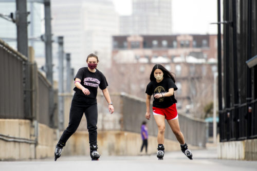 Roommates Jackie Helliwell, who studies environmental engineering, and Tessa Rigby, who studies data science and psychology, try out a new rollerskating hobby near Carter Field. Photo by Ruby Wallau/Northeastern University