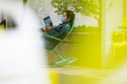 A student reads a book at Richardson Plaza on Northeastern’s Boston campus. Photo by Matthew Modoono/Northeastern University