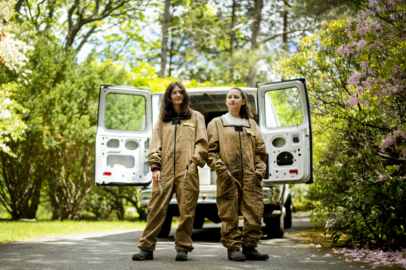Two students in beekeeper suits in front of a van