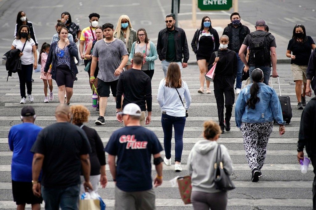 Pedestrians, some with masks, some without walk along the Las Vegas Strip on April 27, 2021