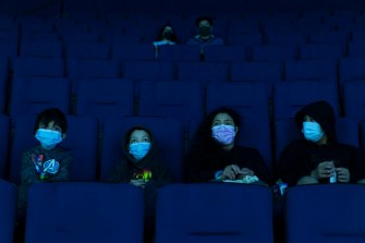 Visitors wear face masks while watching a presentation in a theater at the Aquarium of the Pacific on its first day of reopening to public in Long Beach, Calif. on March 16, 2021.
