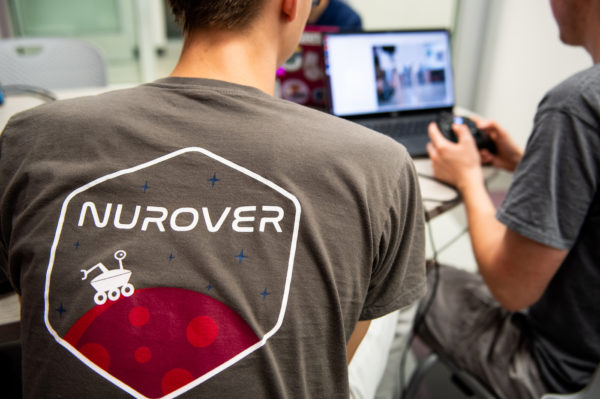 student with NUROVER T-shirt works on computer