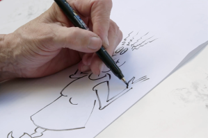 A hand sketching a comic book style face.