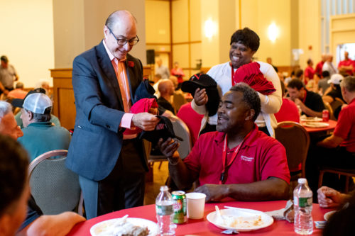 Joseph E. Aoun, president of Northeastern, hands out hats during the facilities summer BBQ held in the Curry Student Center Ballroom. Photo by Matthew Modoono/Northeastern University