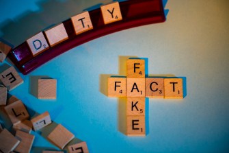 Scrabble letters spell out "fact" and "fake."