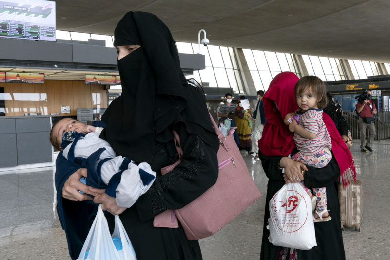 Families evacuated from Kabul, Afghanistan, walk through the terminal before boarding a bus after they arrived at Washington Dulles International Airport, in Chantilly, Va., on Monday, Aug. 23, 2021.