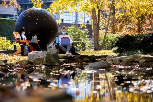 Brianna Daphnis, who studies biology, and Anya Korbut, who studies industrial engineering, study outside during a sunny fall day by the Koi Pond. Photo by Ruby Wallau/Northeastern University