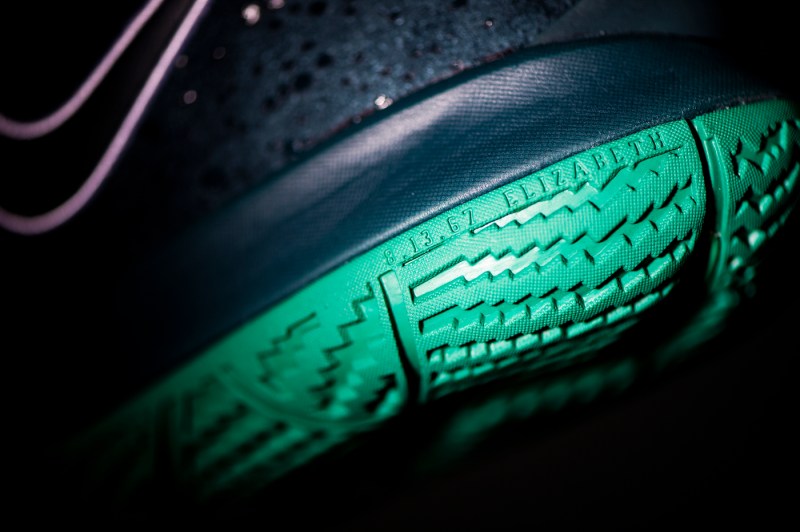 up close of black and green nike shoe with engraving