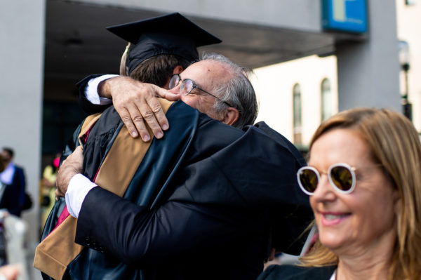 northeastern graduate hugs an older man