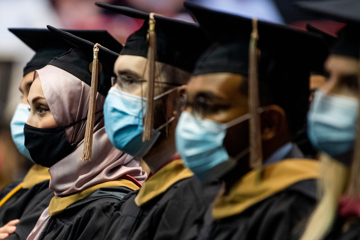 masked northeastern doctoral graduates wearing caps