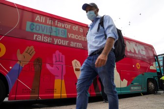 masked man walking by nyc mobile vaccine clinic bus