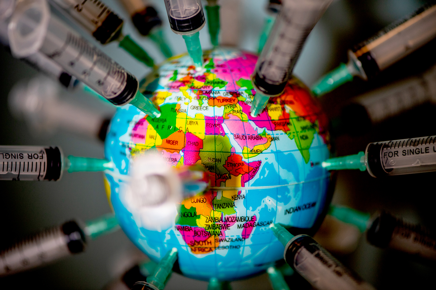 syringes stuck into a model globe