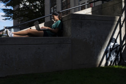 Northeastern biomedical physics major Kyla Pelham takes advantage of the warm temperatures and works on her physics lab outside. Photo by Alyssa Stone/Northeastern University