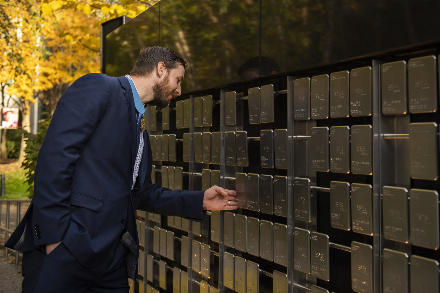 man in suit and tie examines rows of plaques
