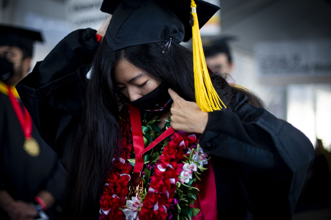 a graduate holds on to a cap, while checking the rest of their outfit