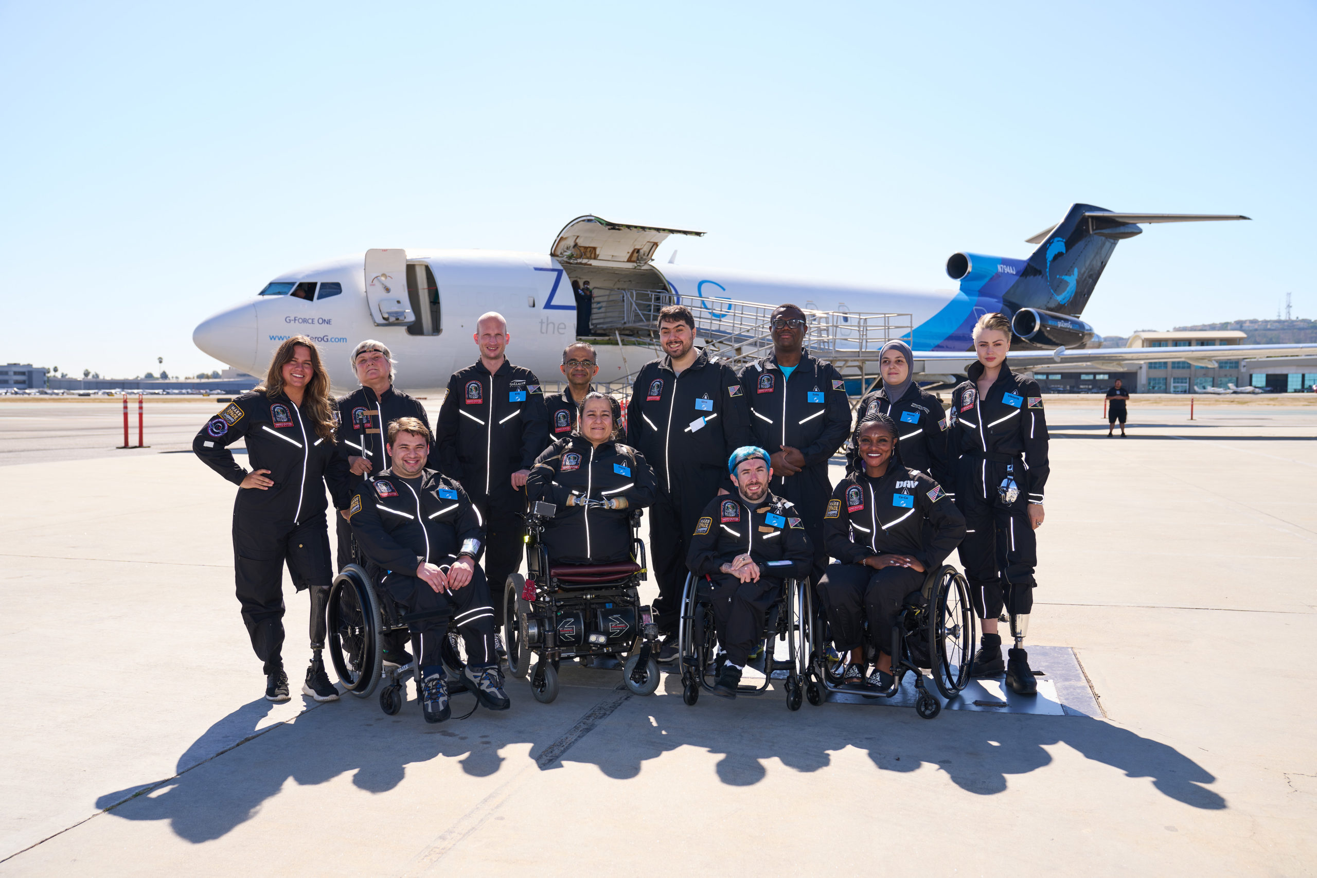 group of people standing or sitting in wheelchairs on airport tarmac in front of a plane before spaceflight