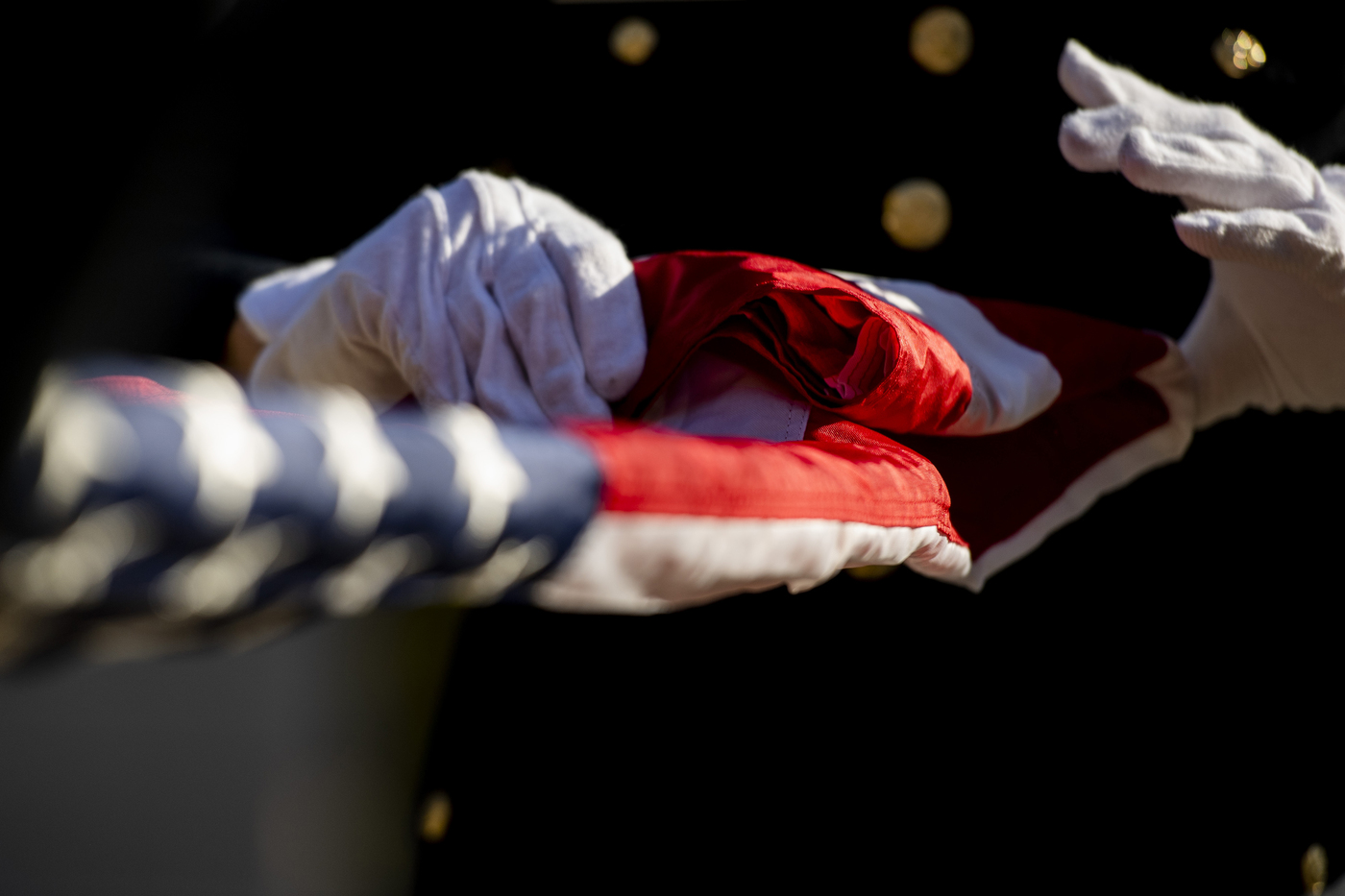white gloved hands folding a us flag