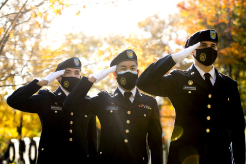 three rotc members in uniform standing at salute