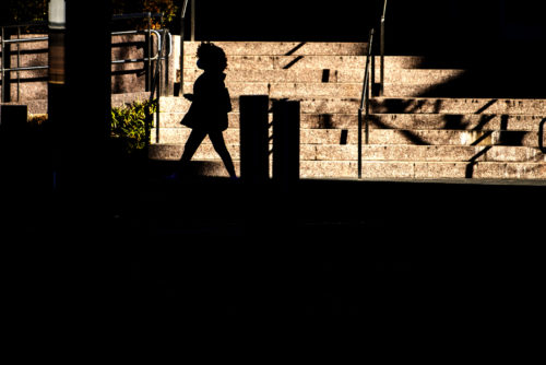 A member of the Northeastern community is silhouetted by sun shining on the Snell Library steps.  Photo by Matthew Modoono/Northeastern University