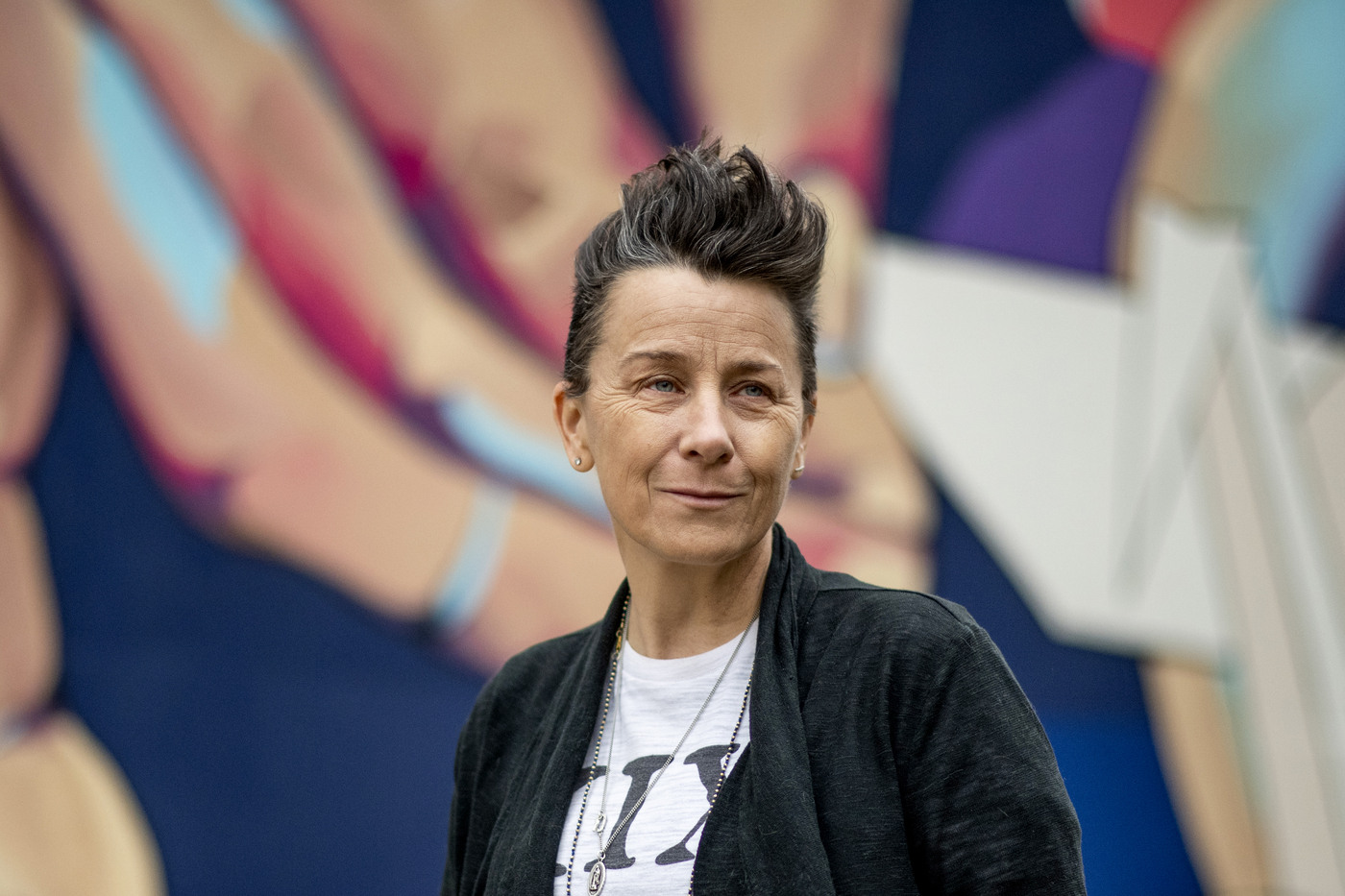 melissa ferrick stands in front of a mural