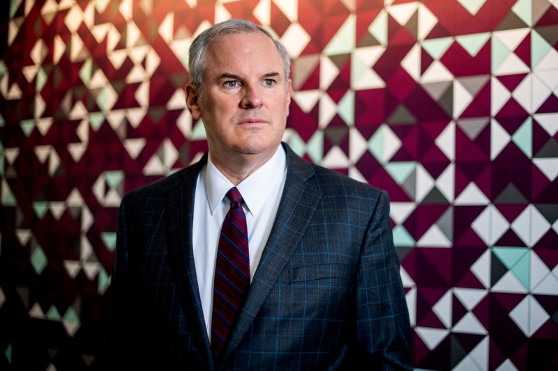 Stephen Flynn, director of the Global Resilience Institute, in a full suit, looking off into the distance against a red and white checkered backdrop.