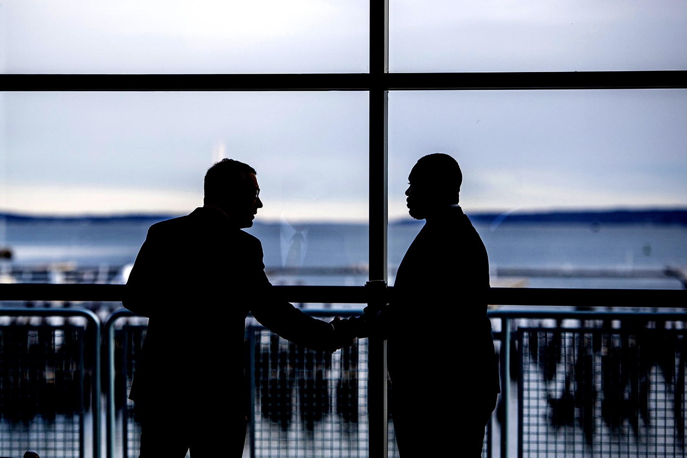 Two people in silhouette shaking hands at an airport