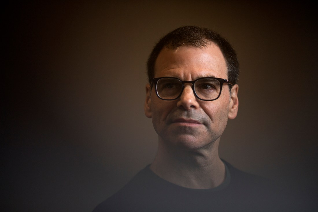 Portrait of Matthew Miller wearing glasses on a dark background with a fade overlay effect.