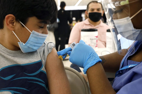 Shivam Patel, 13, receives his first Pfizer COVID-19 vaccination from nurse Diawna Jenkins as his father, Rajesh Patel, observes from the background at the Cook County Public Health Department on May 13, 2021, in Des Plaines, Ill. AP Photo by Shafkat Anowar
