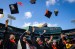 Graduate students fling their caps in the air.