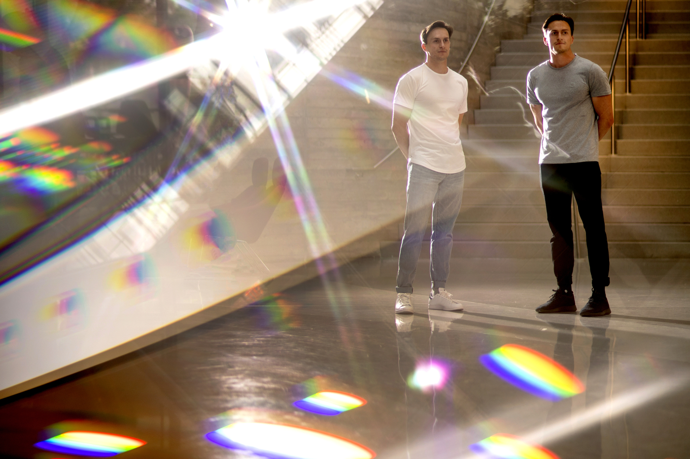 Jake and Jared Covell standing in an open, modern building, with sunlight catching and making rainbows