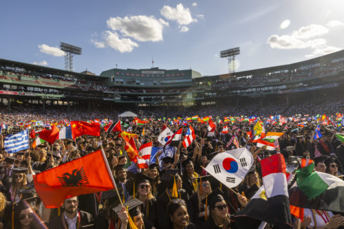 a large crowd of students waving flags from different countries