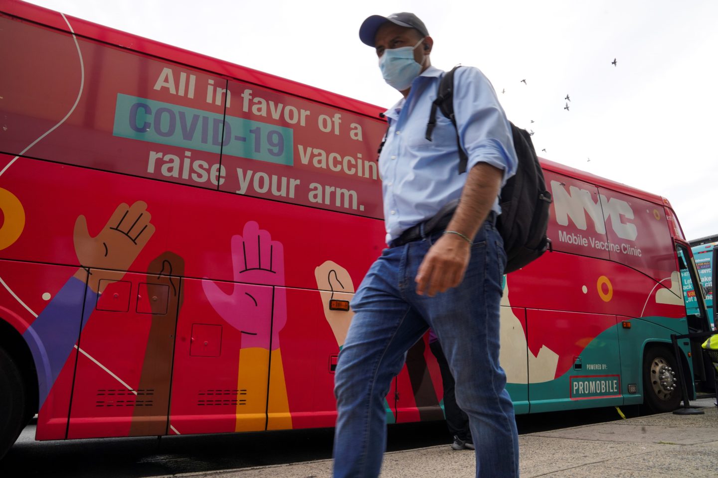 masked man walking by nyc mobile vaccine clinic bus