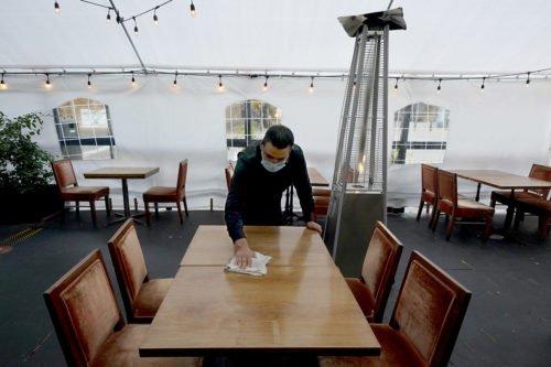 Fabian Rodriguez cleans a table in an outdoor tented dining area of Tequila Museo Mayahuel restaurant, in Sacramento, Calif. on Nov. 19, 2020. AP Photo by Rich Pedroncelli