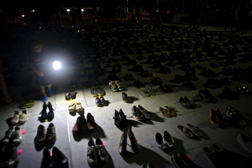 A child illuminates hundreds of shoes at a memorial for those killed by Hurricane Maria, in front of the Puerto Rico Capitol, in San Juan, Friday, June 1, 2018. AP Photo/Ramon Espinosa