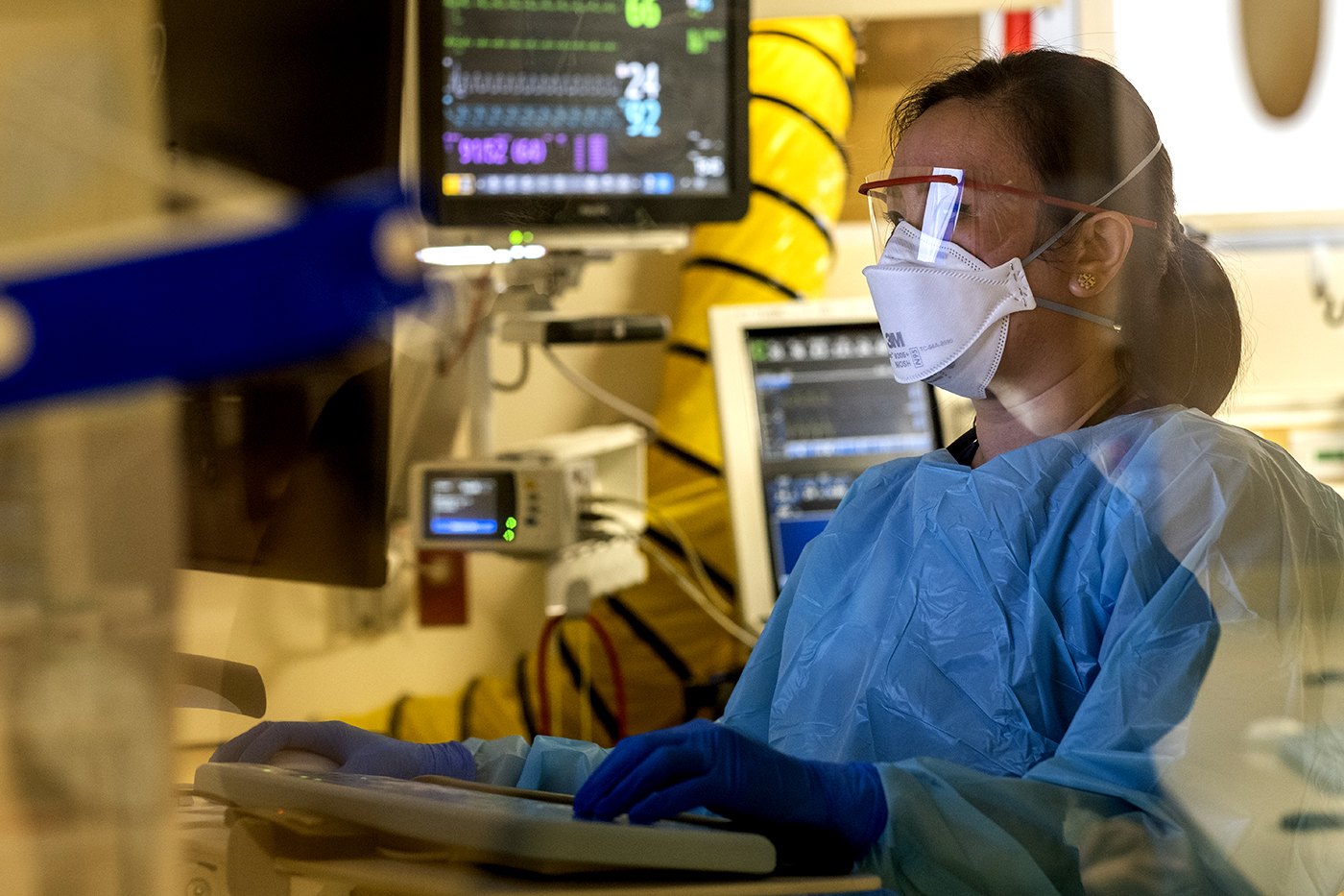 A physician covered in PPE at the computer