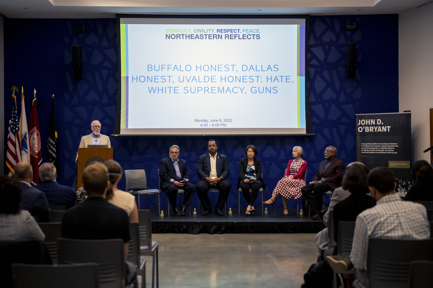 A presentation to a crowded room where the first slide is 'Buffalo honest, Dallas Honest, Uvalve Honest: Hate, White Supremacy, Guns' 