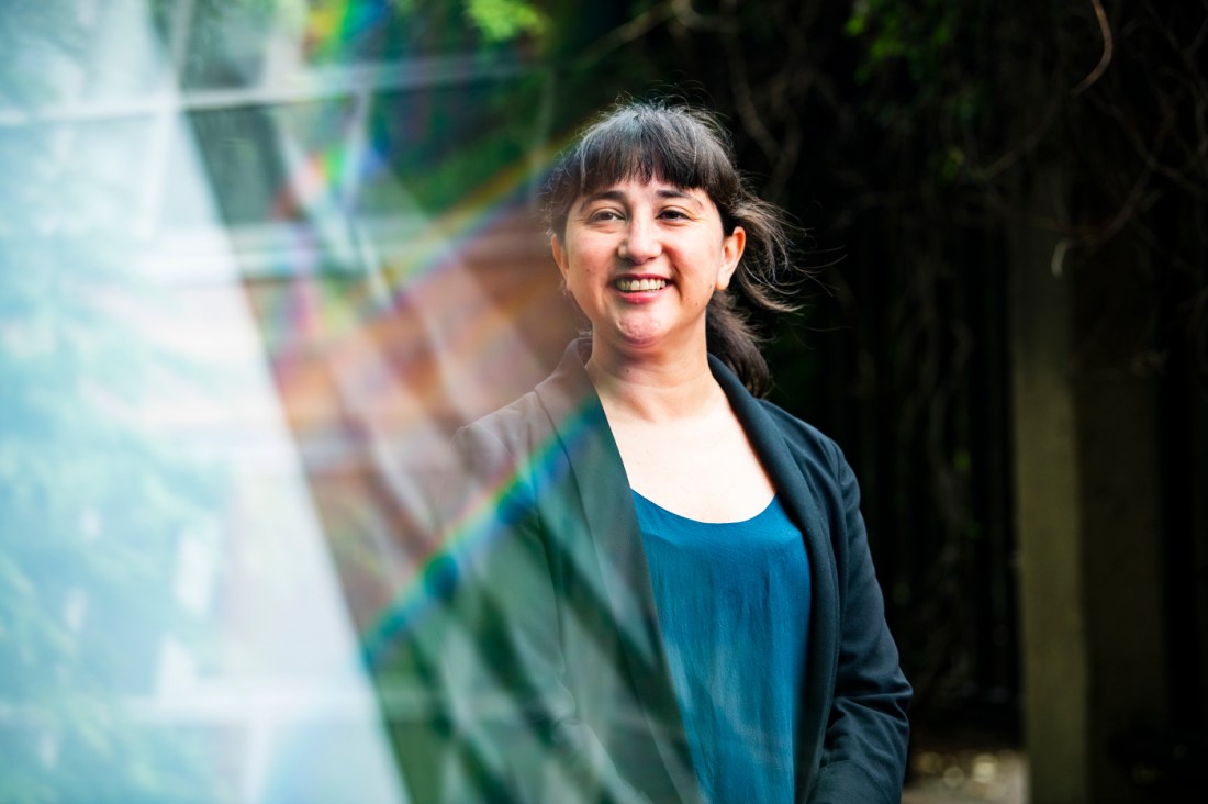 A woman with dark hair and wearing a black blazer poses for a photograph