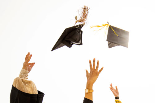 hands tossing graduation caps into the air