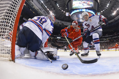 Russia's Ivan Muranov, center, and USA's Phil Kemp struggle for a puck while USA's goaltender Cayden Primeau looks behind him during the Ice Hockey 2019 World Junior championships match between Russia and USA in Vancouver, Canada. Chris Barry / Sputnik  via AP
